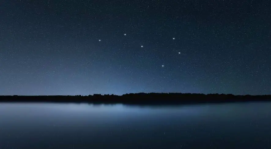 A lake with several stars in the sky.